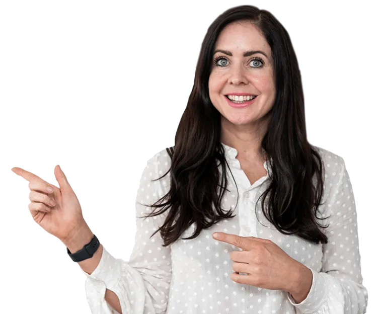 A woman with long dark hair, wearing a white polka dot blouse, smiles and points to her left with both hands.